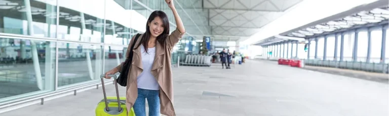 Traveler with suitcase waving in an airport arrivals hall