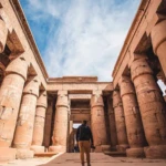 Visitor walking between giant columns of an ancient temple
