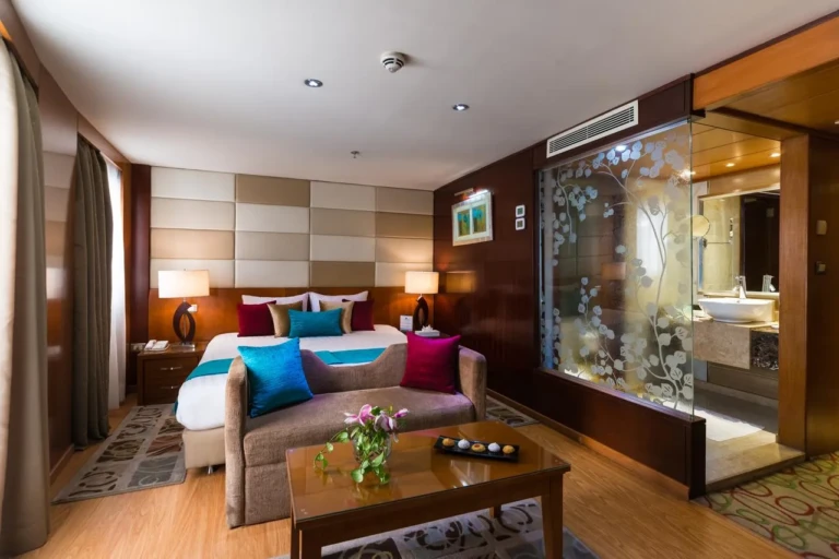 Esmeralda suite bedroom with sofa and glass-walled bathroom