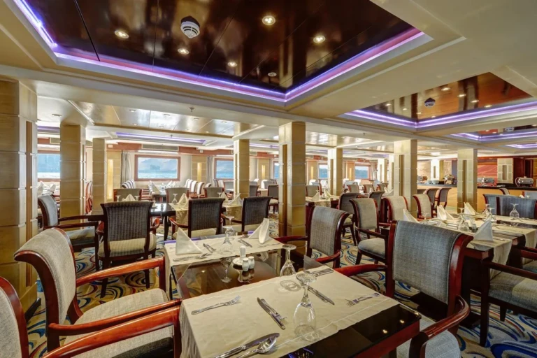 Esmeralda dining tables under a purple-lit ceiling