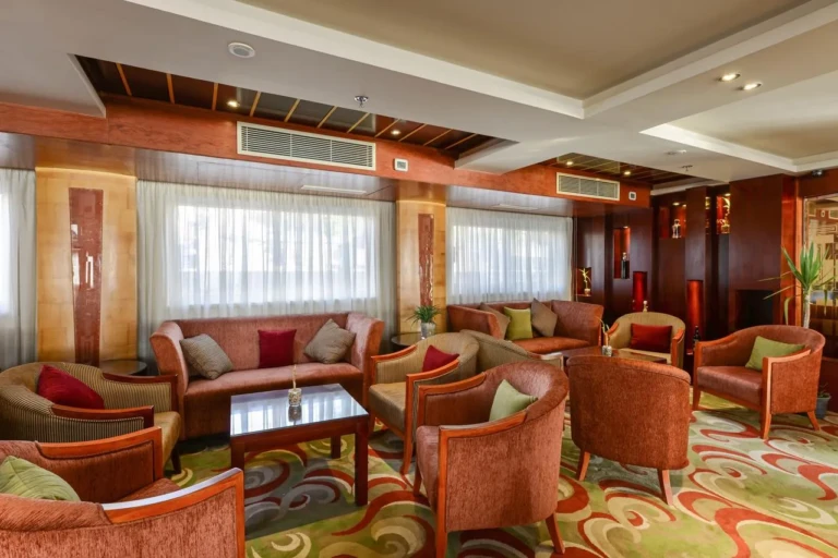 Esmeralda lounge with armchairs and sofas by curtained windows