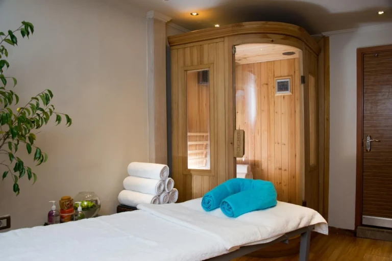 Esmeralda spa massage table beside a wooden sauna cabin