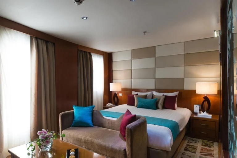 Esmeralda double bed with sofa at its foot and curtained window