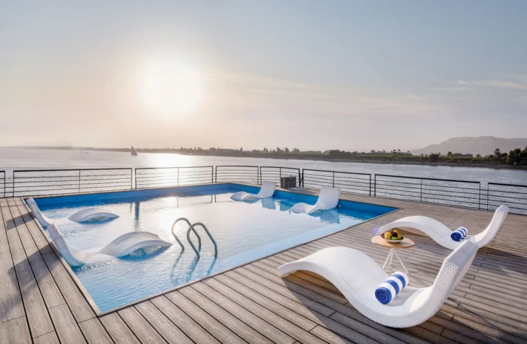 Historia sun deck pool with white sun loungers at sunset