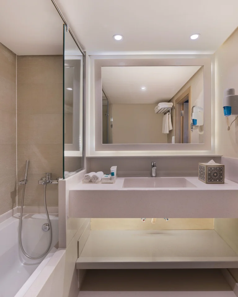 Bathroom with bathtub, vanity and backlit mirror