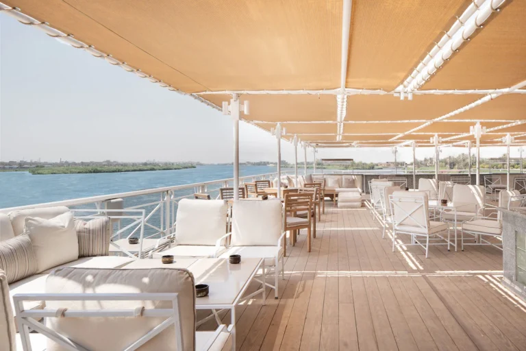 Shaded deck lounge with sofas and tables beside the river
