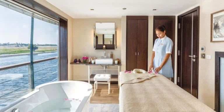 Spa treatment room with massage bed and bathtub by a Nile window