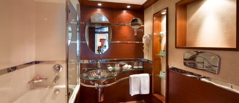 Amwaj Living Stone bathroom with bathtub and glass-shelf vanity
