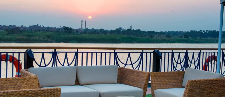 Wicker sofas on the Amwaj Living Stone deck at sunset over the Nile