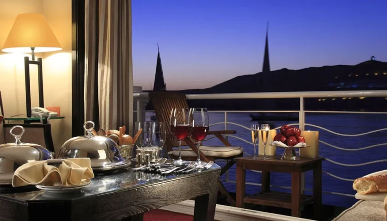 Balcony dinner table with wine glasses at dusk on MS Jaz Senator