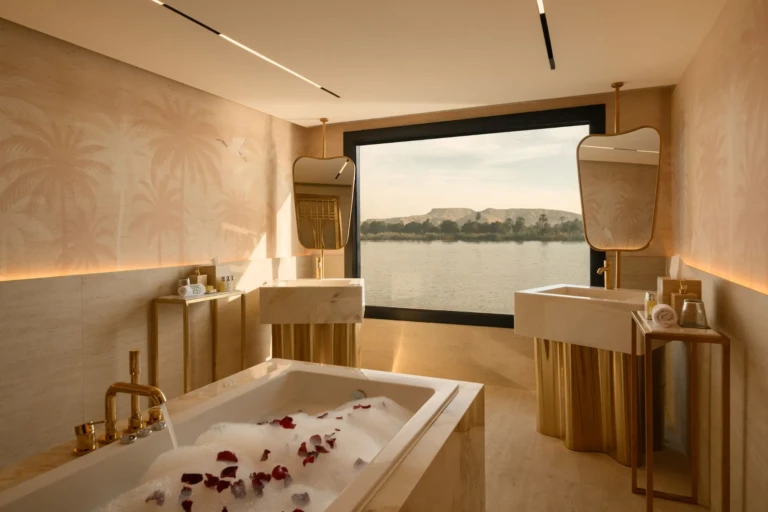 Bathtub with rose petals and twin sinks facing a Nile window