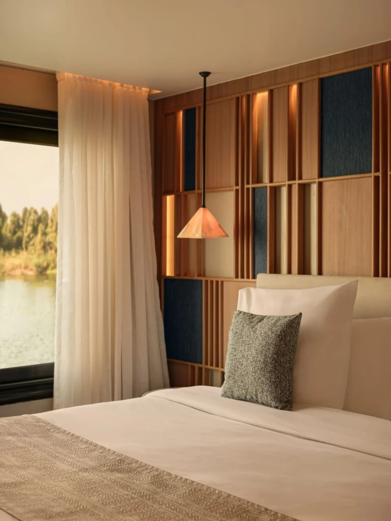 Cabin bed with pendant lamp and wooden headboard wall by the Nile