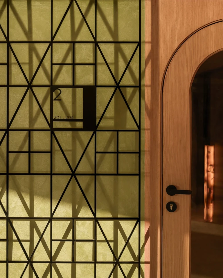 Geometric metal screen beside an arched wooden door on Le Fayan