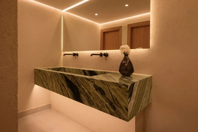 Green marble washbasin with backlit mirror in a Le Fayan restroom
