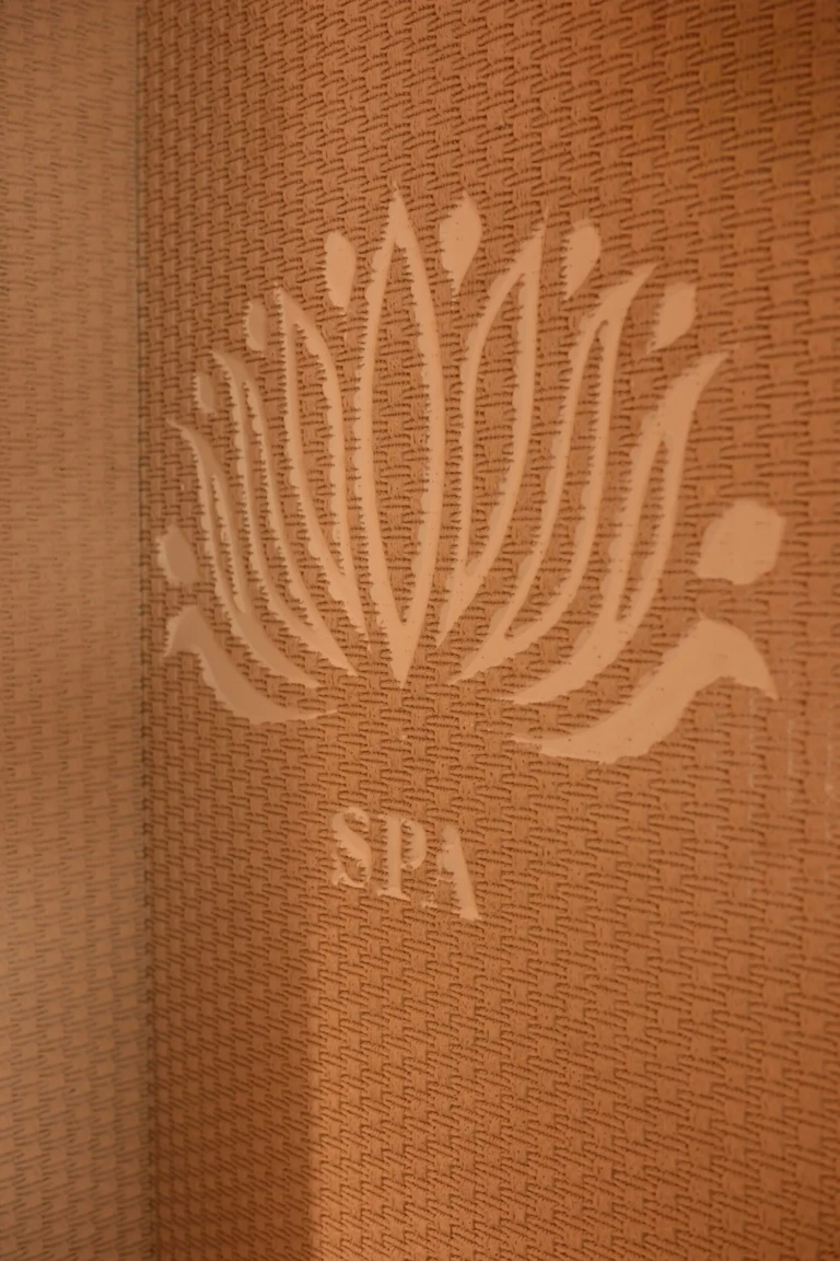 Spa sign with lotus emblem on a textured wall aboard Le Fayan
