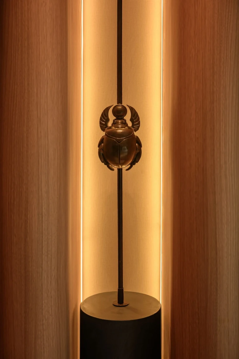 Bronze scarab sculpture on a backlit pole aboard Le Fayan