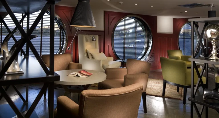 MS Mayfair library corner with armchairs and porthole windows