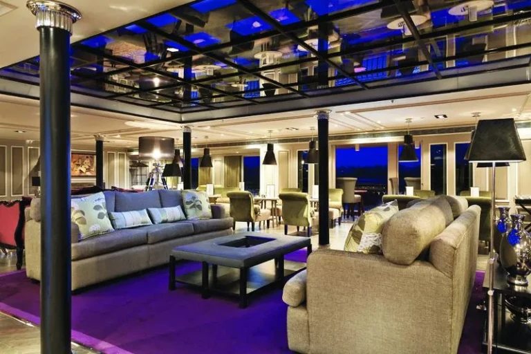 Lounge seating on purple carpet beneath a lit skylight, MS Mayfair