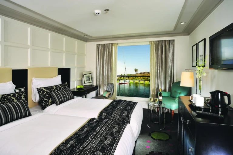 Twin beds and teal armchair in an MS Mayfair cabin with Nile view