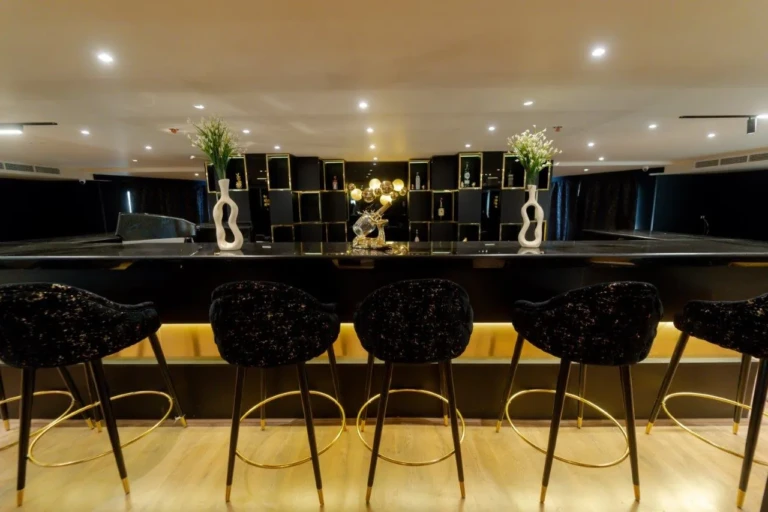 Bar counter with black stools and backlit shelves
