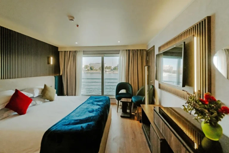 Double bed cabin with teal throw and Nile view window