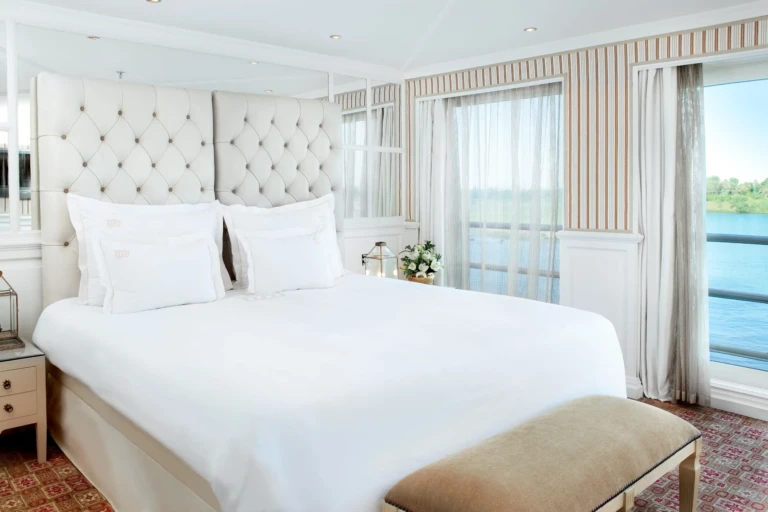 White double bed with tufted headboard by a Nile window