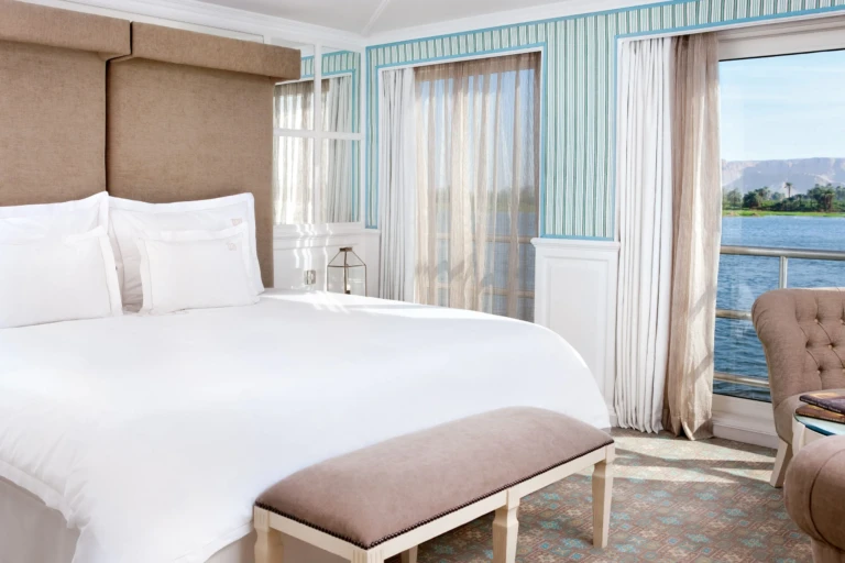 Double bed and bench beside a window to the riverbank