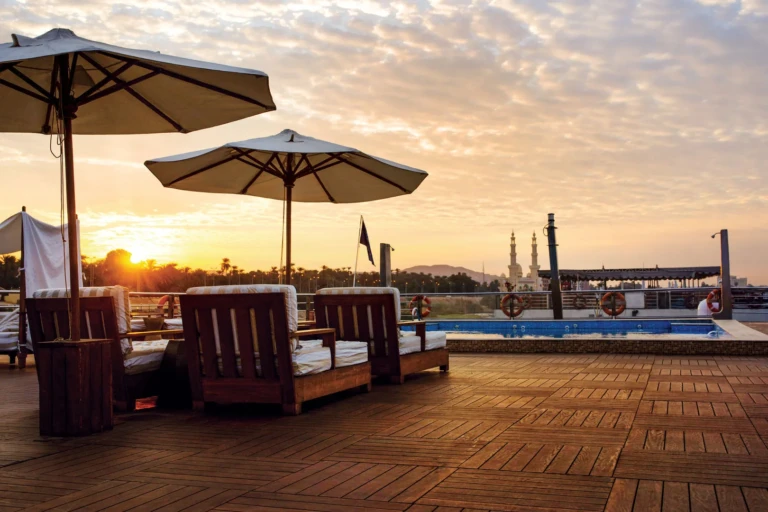 Sun deck daybeds and parasols by the pool at sunset