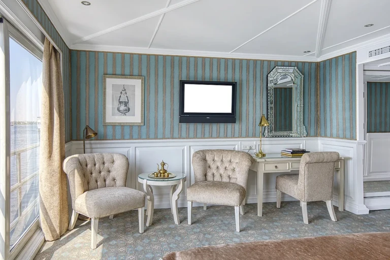 Suite sitting area with tufted armchairs, desk and TV