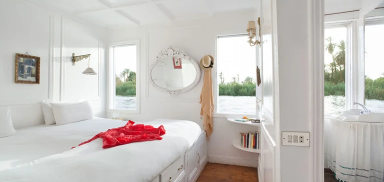 Bright cabin with a red throw on the bed on the Meroe dahabiya