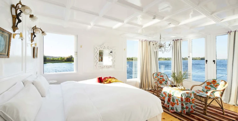 Cabin with bed, mirror and armchairs by Nile windows on the Meroe