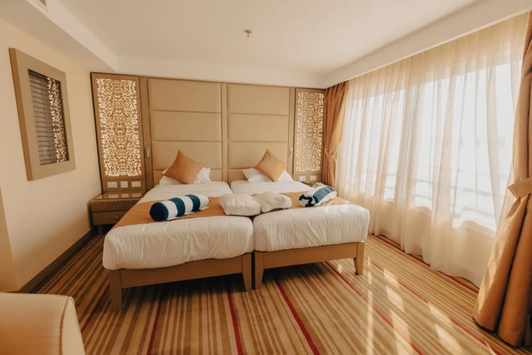 Twin cabin with two beds and sheer curtains on the Nebu