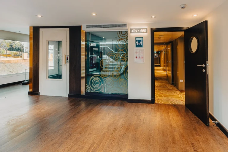 Lift and glass doors in a wood-floored hallway on the Nebu