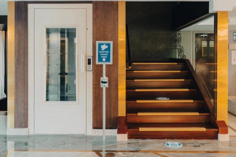 Lift door next to a wooden staircase, front view, on the Nebu