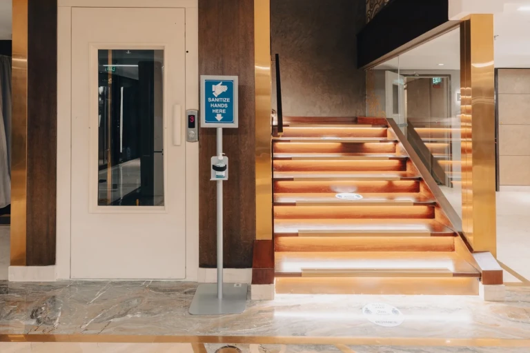 Elevator beside a lit wooden staircase, side angle, on the Nebu