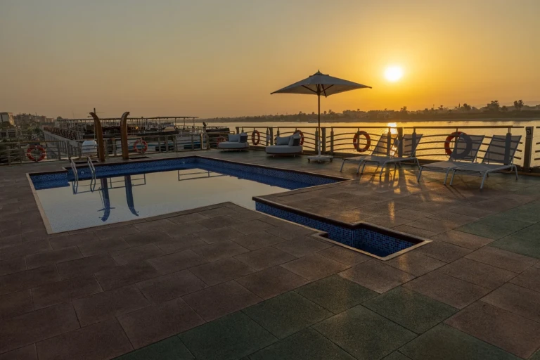 Pool deck with parasol and sun loungers at sunrise on the Nebu