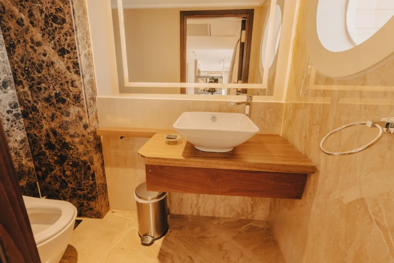 Washbasin on wooden counter with marble walls in a Nebu bathroom
