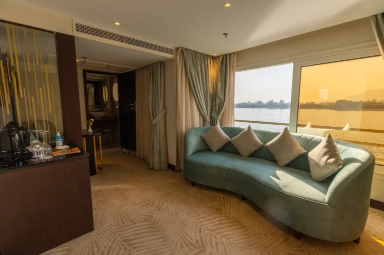 Curved teal sofa beside a sunset window in a Nebu suite
