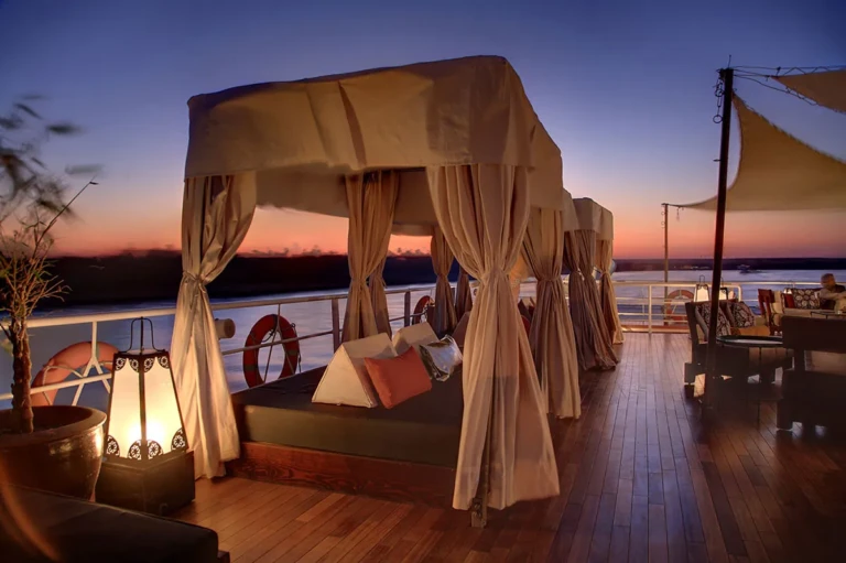 Canopied daybed on deck at sunset with lanterns