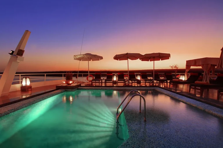 Lit pool with parasols at sunset
