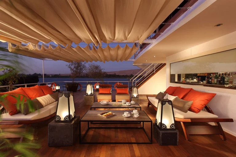 Shaded deck lounge with orange cushions and lanterns at dusk