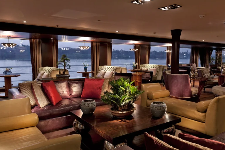 Sun Boat IV lounge with sofas and panoramic Nile windows at dusk