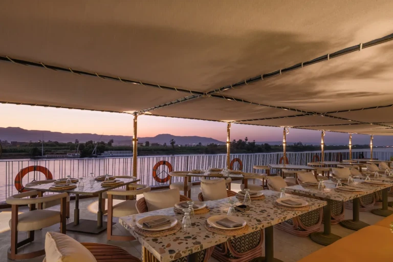 Shaded outdoor dining tables on the Soleil sun deck at sunset