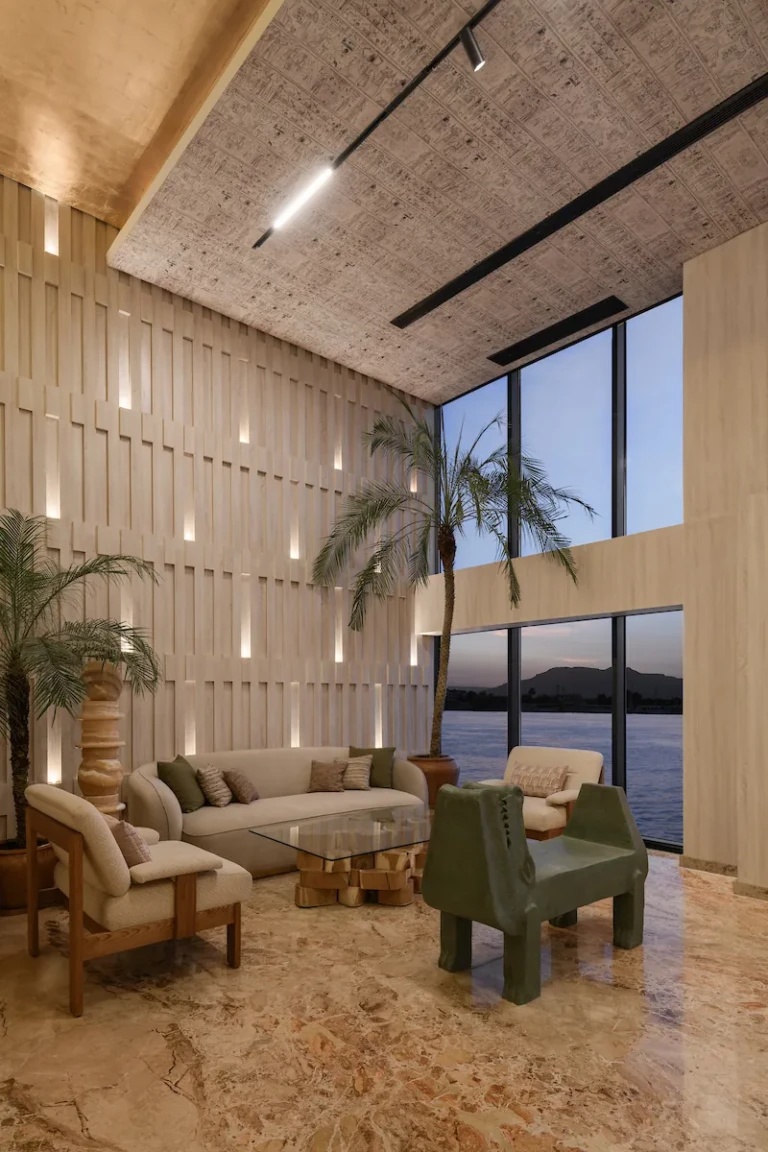 Double-height lounge with sofa, palm and tall windows on the Soleil