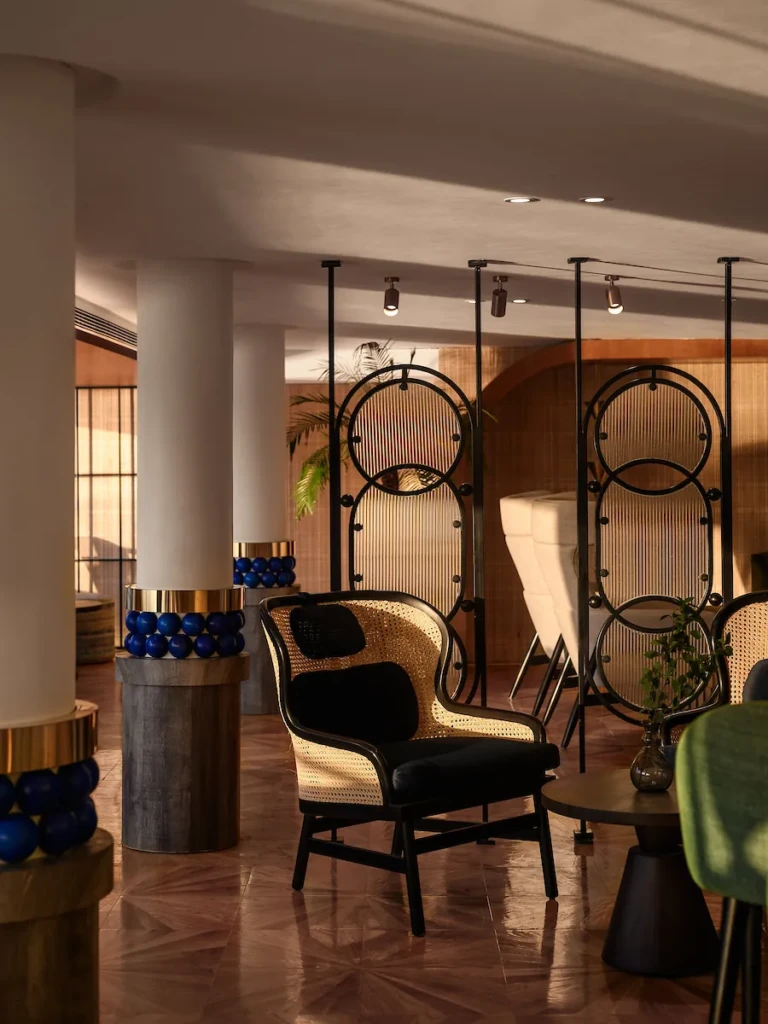 Soleil lounge rattan armchair beside decorative metal screens
