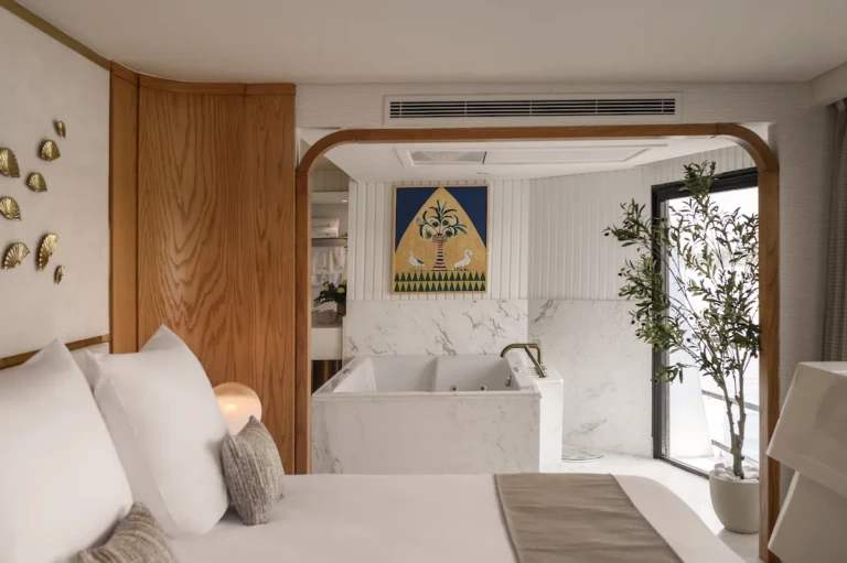 Soleil suite bedroom with freestanding bathtub behind an arched opening