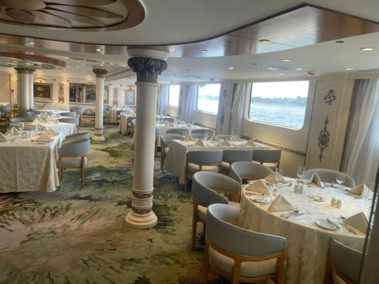 Restaurant tables set beside large Nile view windows