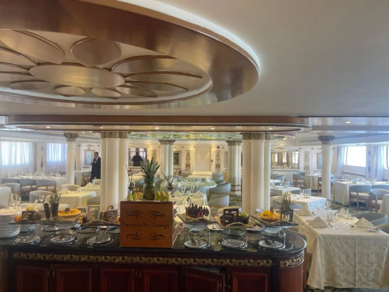 Restaurant buffet station with white-clothed tables beyond