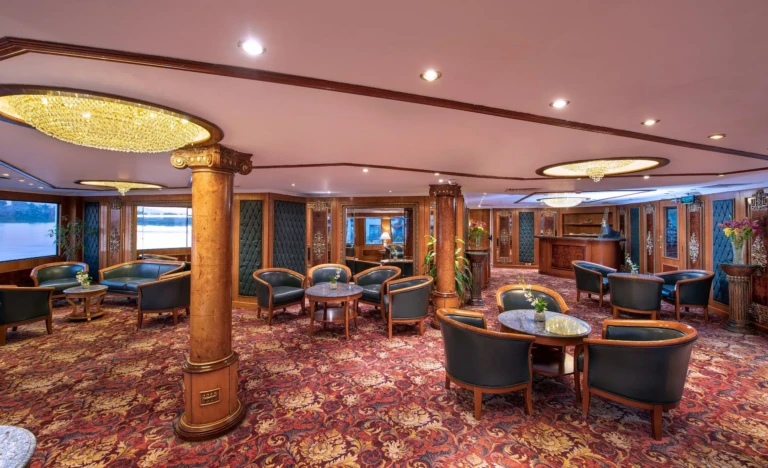Lounge with armchairs, wooden columns and patterned red carpet