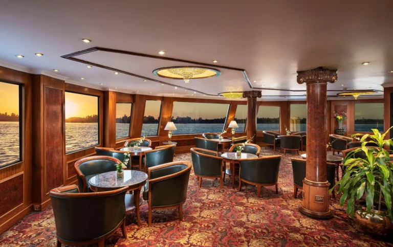Lounge armchairs and tables with Nile sunset through windows